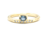 Oval faceted blue sapphire ring in prongs setting with tiny diamonds on 14k gold wood texture design band