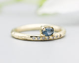 Oval faceted blue sapphire ring in prongs setting with tiny diamonds on 14k gold wood texture design band