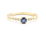 Round faceted blue sapphire ring in prongs setting with tiny diamonds on 14k gold wood texture design band