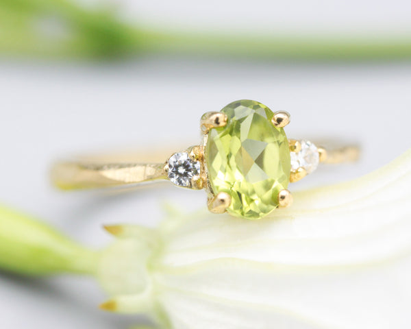 Oval faceted Peridot ring with tiny round diamonds side set gems in prongs setting with 14k gold texture band