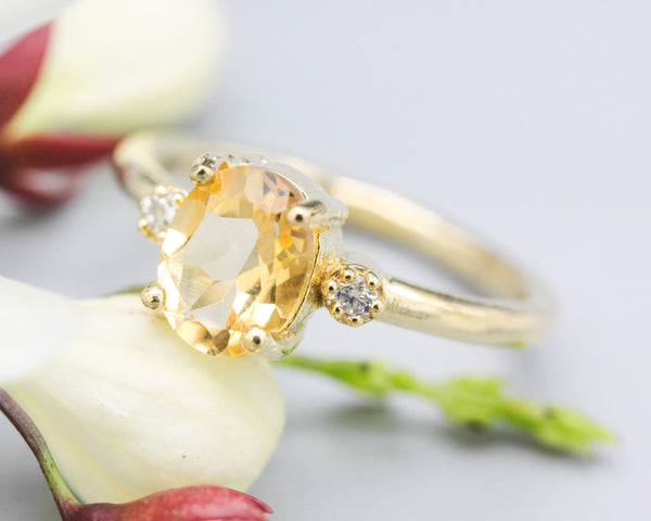 Oval faceted citrine ring with tiny round diamonds side set gems in prongs setting with 14k gold half round band