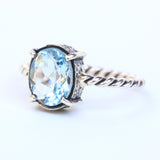Oval faceted Swiss blue topaz ring in silver bezel and prongs setting on sterling silver oxidized twist design band - Metal Studio Jewelry