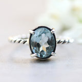 Oval faceted Swiss blue topaz ring in silver bezel and prongs setting on sterling silver oxidized twist design band - Metal Studio Jewelry