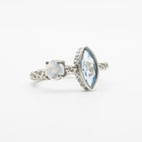Marquis faceted blue topaz ring in silver bezel setting and round moonstone on the side with sterling silver hard texture band - Metal Studio Jewelry