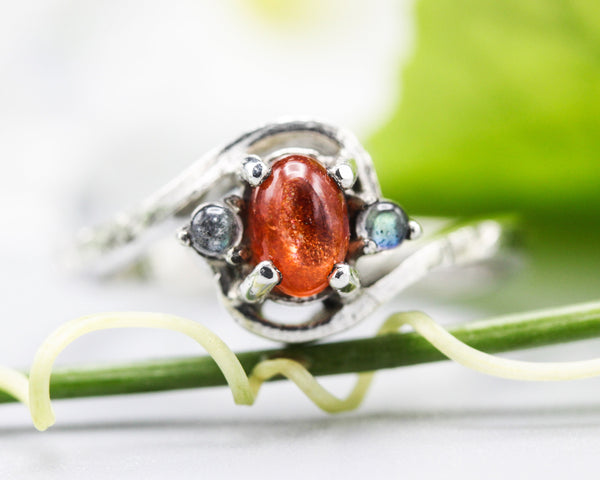Oval sunstone ring with tiny labradorite side set gems in prongs setting with sterling silver texture band