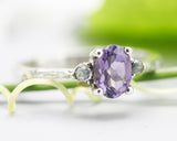 Oval faceted amethyst ring with tiny labradorite side set gems in prongs setting with sterling silver texture oxidized band