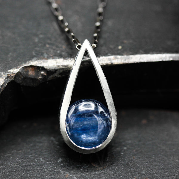 Silver teardrop pendant necklace with round cabochon blue kyanite gemstone on oxidized sterling silver chain