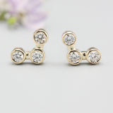 18k gold stud earrings featuring three round diamonds in a bezel setting