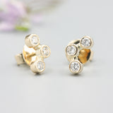 18k gold stud earrings featuring three round diamonds in a bezel setting