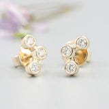 18k gold stud earrings featuring three round diamonds in a bezel setting