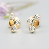 18k gold stud earrings featuring three round diamonds in a bezel setting