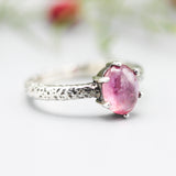 Oval pink sapphire ring in prongs setting with sterling silver hammer texture band