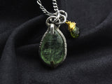 Green kyanite pendant on dark fabric