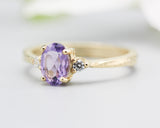 Oval faceted amethyst ring with tiny round diamonds side set gems in prongs setting with 14k gold texture band