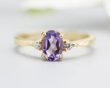 Oval faceted amethyst ring with tiny round diamonds side set gems in prongs setting with 14k gold texture band