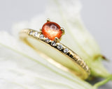 Oval cabochon sunstone ring in prongs setting with tiny diamonds on 14k gold line texture design band