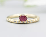 Oval faceted ruby ring in prongs setting with tiny diamonds on 14k gold hammer texture design band