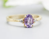 Oval faceted amethyst ring with tiny round diamonds side set gems in prongs setting with 14k gold texture band