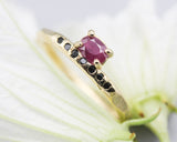 Oval faceted ruby ring in prongs setting with tiny black spinel on 14k gold geometric design band