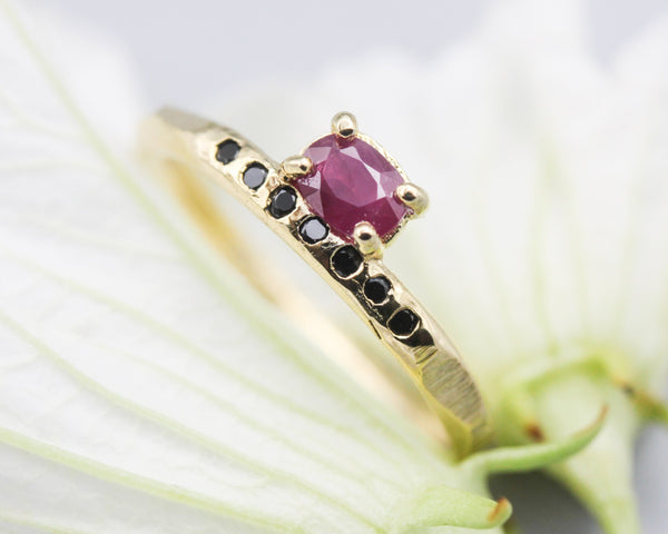 Oval faceted ruby ring in prongs setting with tiny black spinel on 14k gold geometric design band