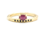 Oval faceted ruby ring in prongs setting with tiny black spinel on 14k gold geometric design band