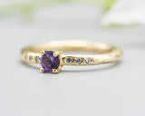 Round faceted amethyst ring in prongs setting with tiny diamonds on 14k gold wood texture design band