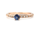 Round faceted blue sapphire ring in prongs setting with tiny diamonds on 14k Rose gold texture design band