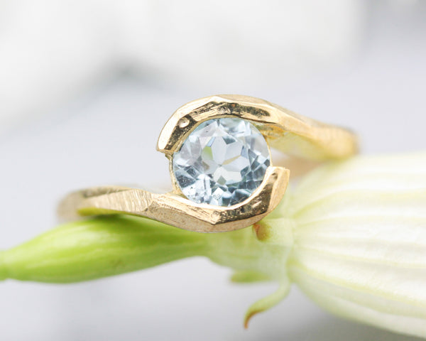Bypass style ring 14k gold geometric texture design with round faceted Blue topaz at the center