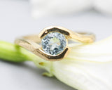 Bypass style ring 14k gold geometric texture design with round faceted Blue topaz at the center