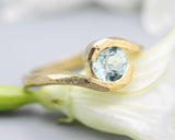 Bypass style ring 14k gold geometric texture design with round faceted Blue topaz at the center