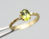 Oval faceted Peridot ring with tiny round diamonds side set gems in prongs setting with 14k gold texture band