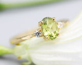 Oval faceted Peridot ring with tiny round diamonds side set gems in prongs setting with 14k gold texture band