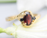 Oval Garnet ring and twin side set black spinel with 14k gold hammer texture band