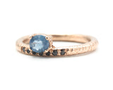 Oval faceted blue sapphire ring in prongs setting with tiny black spinel on 14k Rose gold texture design band