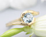 Bypass style ring 14k gold geometric texture design with round faceted Blue topaz at the center