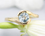 Bypass style ring 14k gold geometric texture design with round faceted Blue topaz at the center