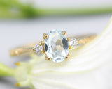 Oval faceted blue topaz ring with tiny round diamonds side set gems in prongs setting with 14k gold texture band