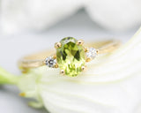 Oval faceted Peridot ring with tiny round diamonds side set gems in prongs setting with 14k gold texture band