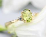 Oval faceted Peridot ring with tiny round diamonds side set gems in prongs setting with 14k gold texture band