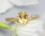 Oval faceted citrine ring with tiny round diamonds side set gems in prongs setting with 14k gold texture band