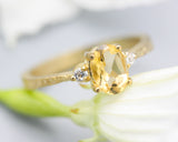 Oval faceted citrine ring with tiny round diamonds side set gems in prongs setting with 14k gold texture band