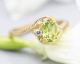 Oval Peridot ring and twin side set diamonds with 14k gold line texture band