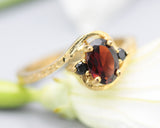 Oval Garnet ring and twin side set black spinel with 14k gold hammer texture band