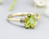 Oval faceted Peridot ring with tiny round diamonds side set gems in prongs setting with 14k gold half round band