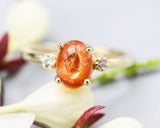 Oval cabochon Sunstone ring with tiny round diamonds side set gems in prongs setting with 14k gold half round band