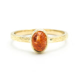 Oval cabochon sunstone ring in bezel setting with 18k gold texture band