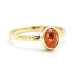 Oval cabochon sunstone ring in bezel setting with 18k gold texture band