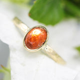 Oval cabochon sunstone ring in bezel setting with 18k gold texture band