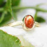 Oval cabochon sunstone ring in bezel setting with 18k gold texture band