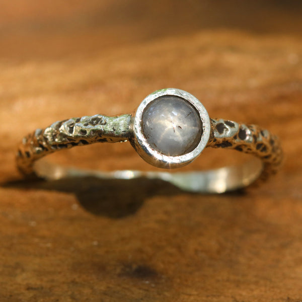 Sterling silver oxidized texture ring with round blue star sapphire in bezel setting at the center - Metal Studio Jewelry